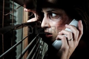 8726455-fearful-battered-woman-peeking-through-the-blinds-to-see-if-her-husband-is-home-while-calling-for-he
