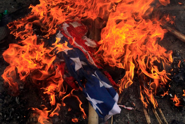 A burning U.S. flag is seen on the ground after it was set on fire by Bangladeshi Muslims during a protest in Dhaka